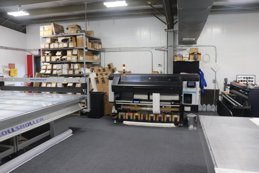 Print shop with rolls of material and large-format printers.